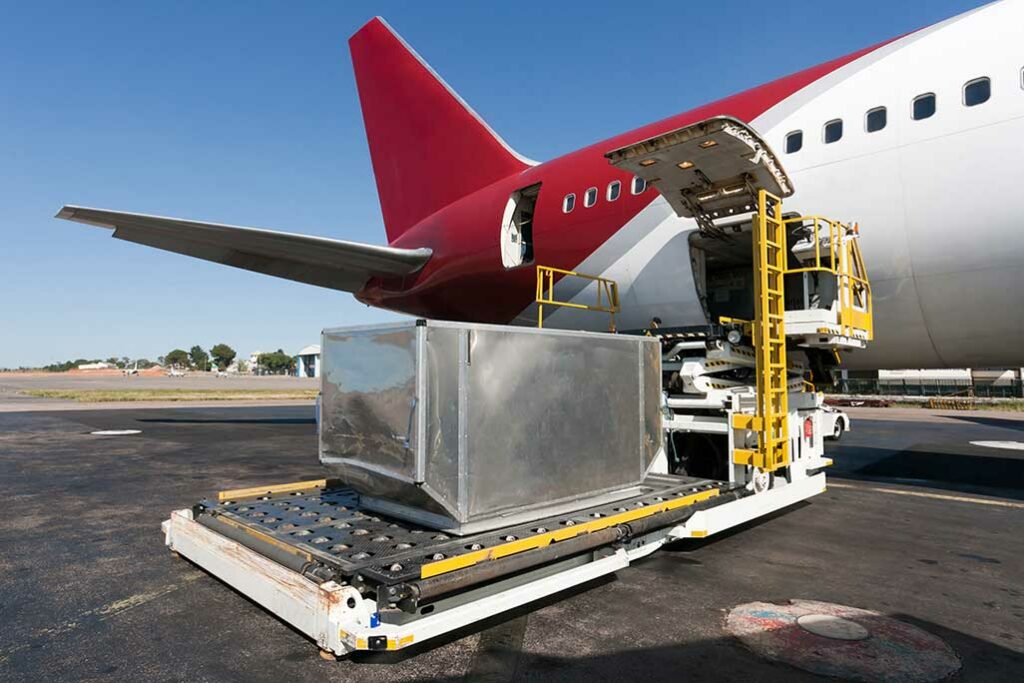 steel storage container being loaded on a red and white plane