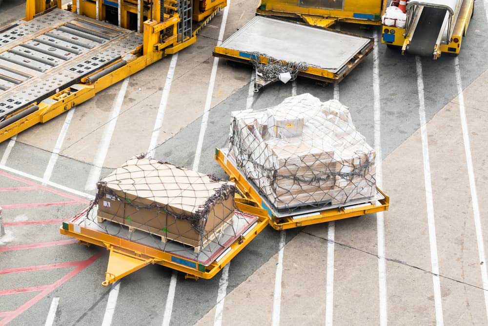 a couple of palleted cargo parked on a runway waiting for transport