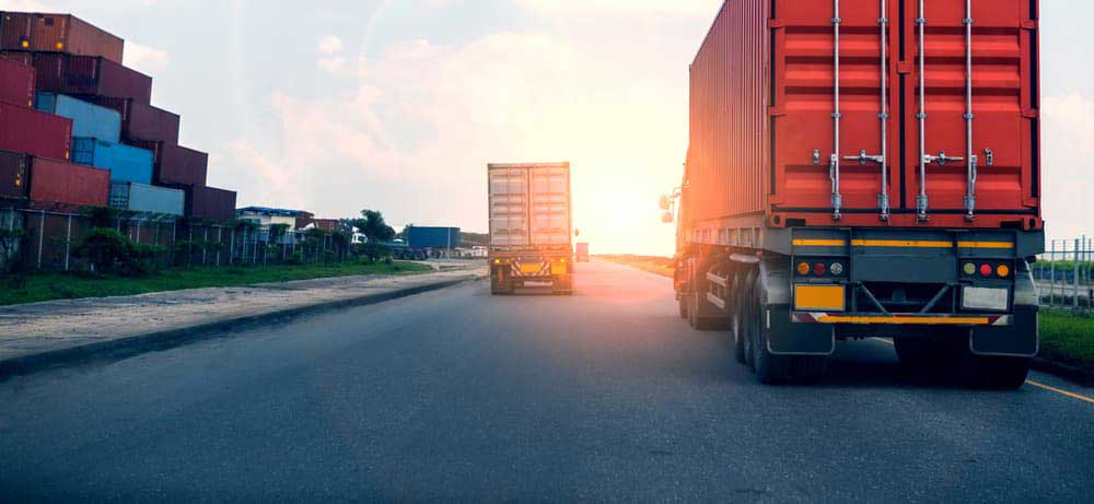 rear view of delivery trucks driving towards the sunset